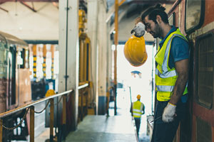 A man wiping his brow as he works in a heated workplace.